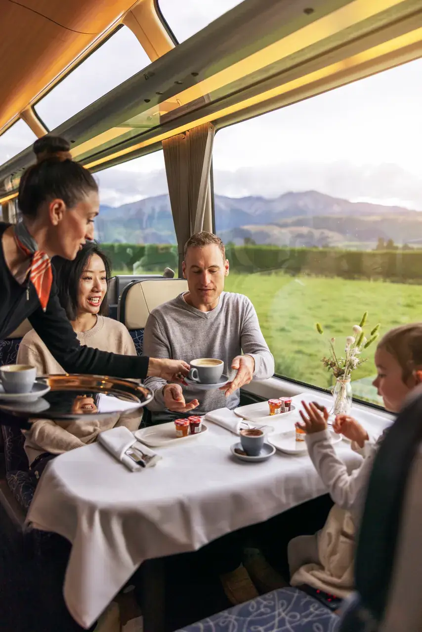 Passengers at a white-linen table aboard a scenic train