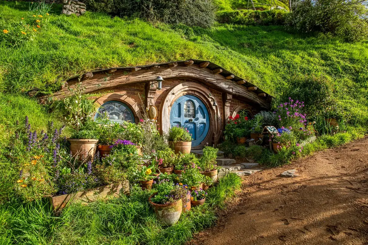 A round green hobbit hole door set into the hillside at Hobbiton