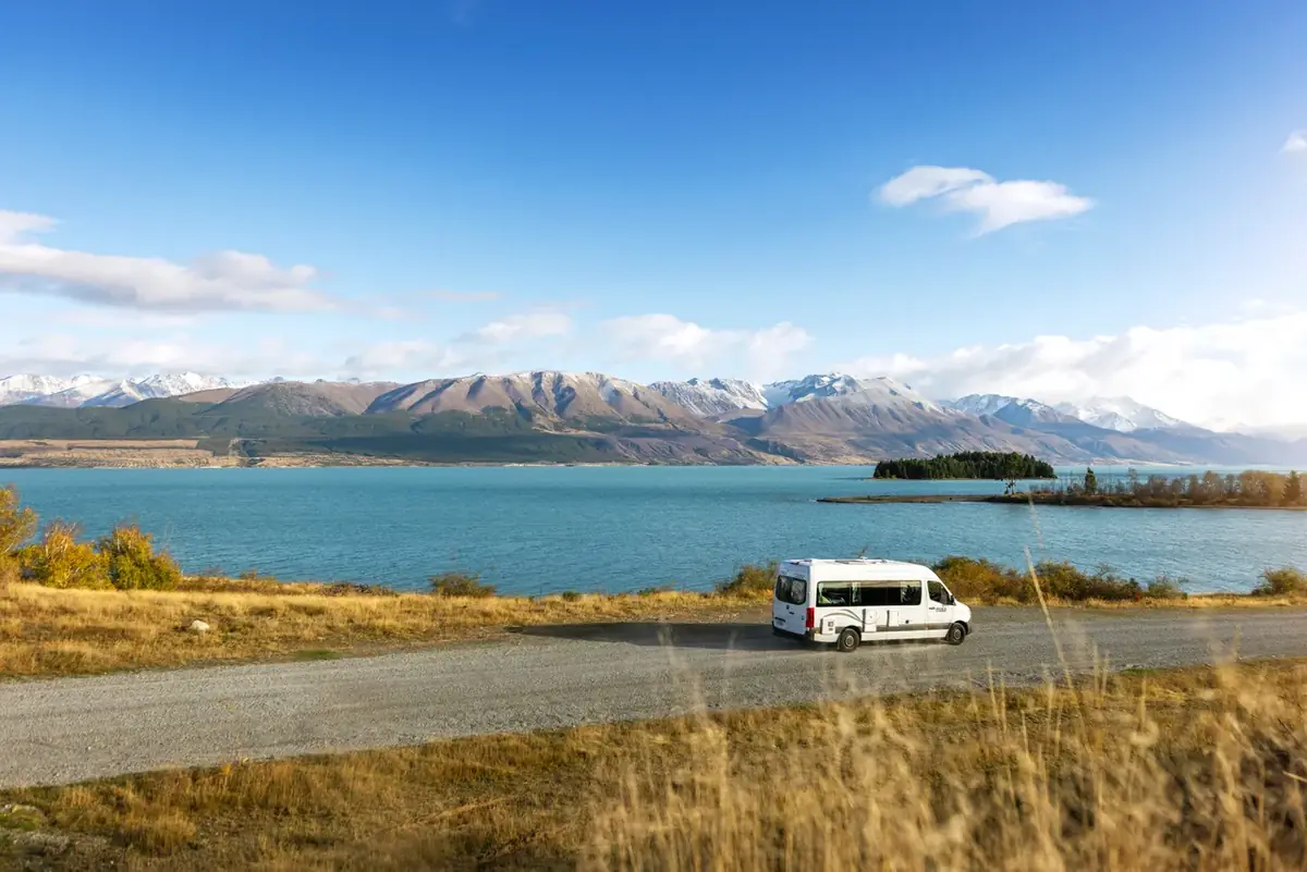 A campervan on the open road beside Lake Pukaki