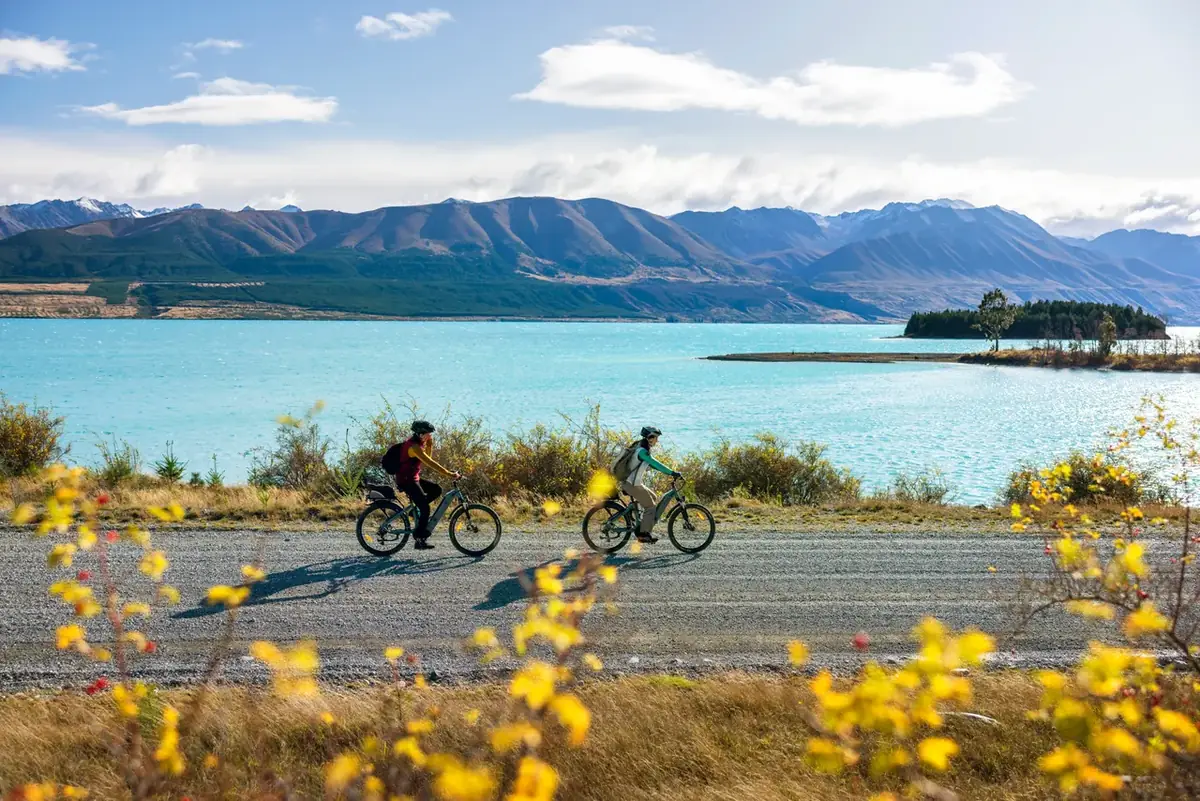 Cyclists on the lakeside trail at Lake Tekapo with the Southern Alps behind