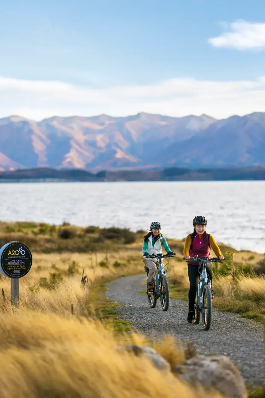 Cyclists on the lakefront trail at Lake Tekapo in spring sunshine