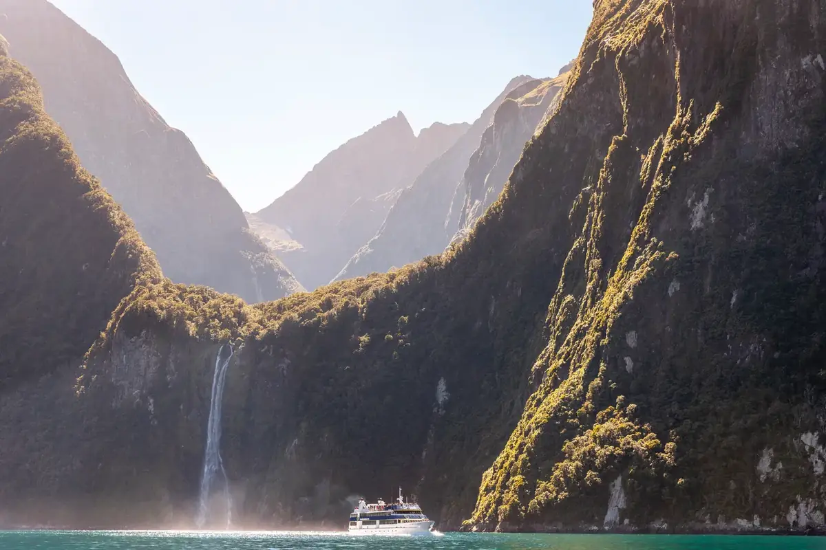 A waterfall pouring into Milford Sound between sheer cliffs