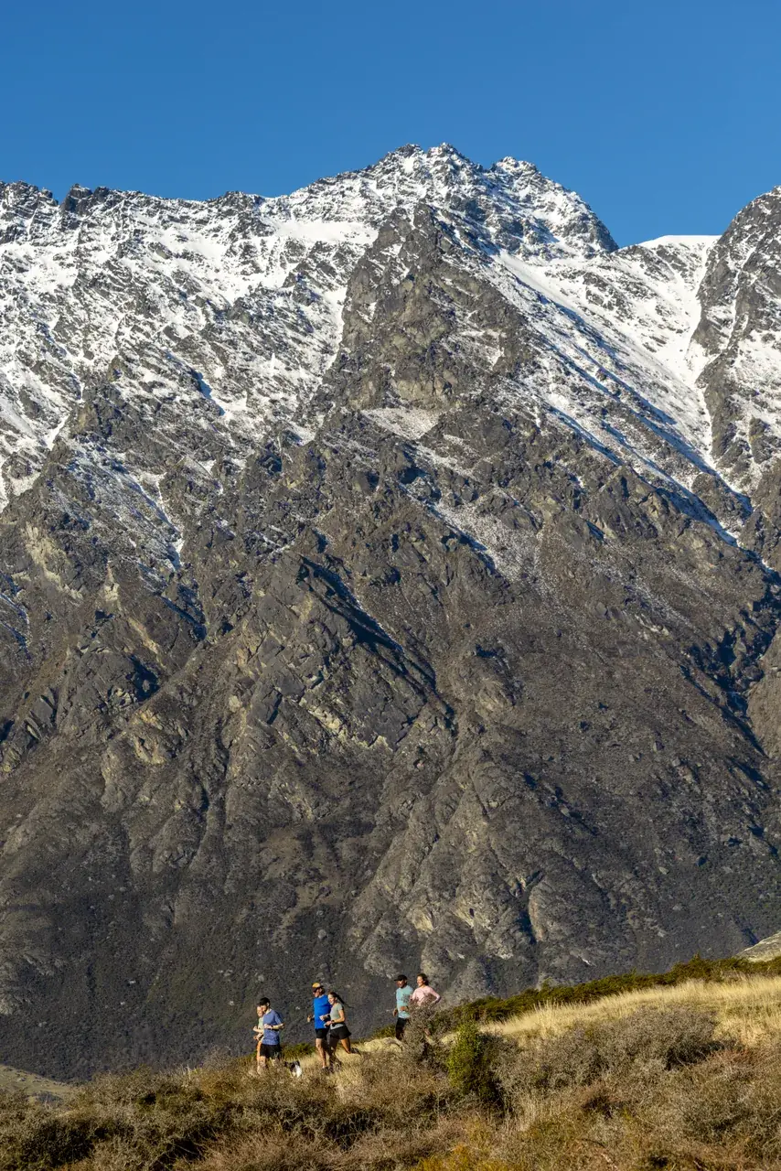 Walkers beneath the rock towers of the Remarkables above Queenstown