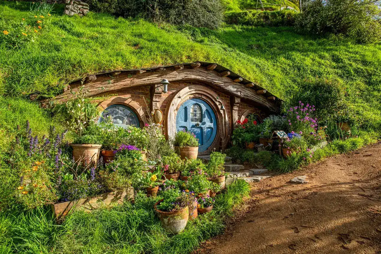 A blue-doored hobbit hole with pots of flowers at Hobbiton